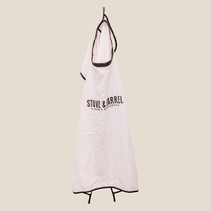 White Stove & Barrel barber apron with black trim, hanging for men's grooming use