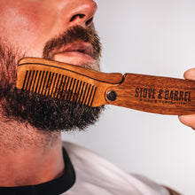 Man grooming thick beard with wooden Stove & Barrel comb, showcasing premium men's grooming tools.