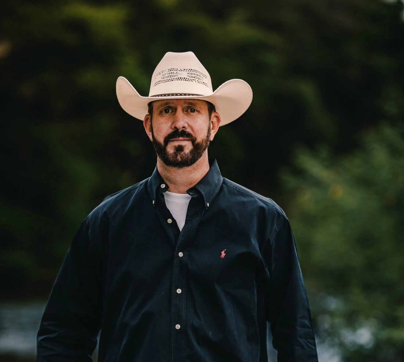 Bearded man in cowboy hat and dark shirt, embodying modern masculinity and rugged style