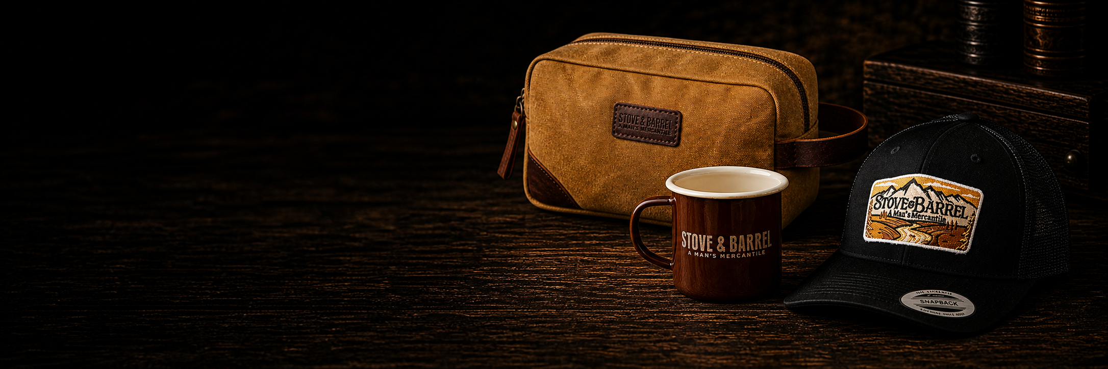 Stove & Barrel men's mercantile gear: canvas toiletry bag, enamel mug, and trucker hat on dark wood
